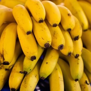 Home Cluster of bright yellow bananas stacked in a market, showcasing freshness and ripeness.