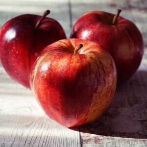 Home Close-up of fresh red apples on a rustic wooden table captured in natural light.