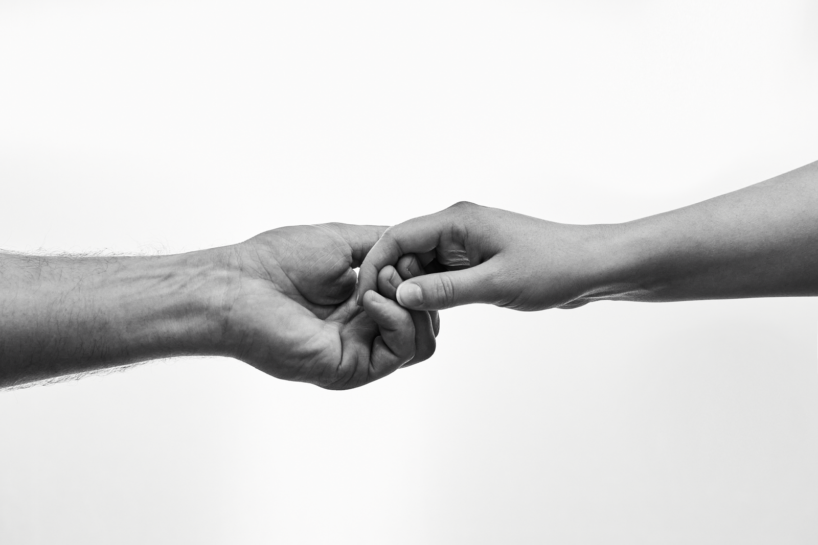 Black and white photo of two hands connecting, symbolizing unity and support.